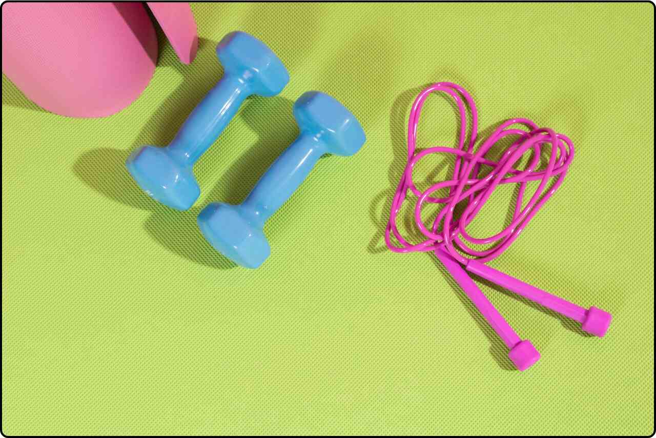 Fitness mat, jumping rope, and dumbbells arranged on a vibrant green background.